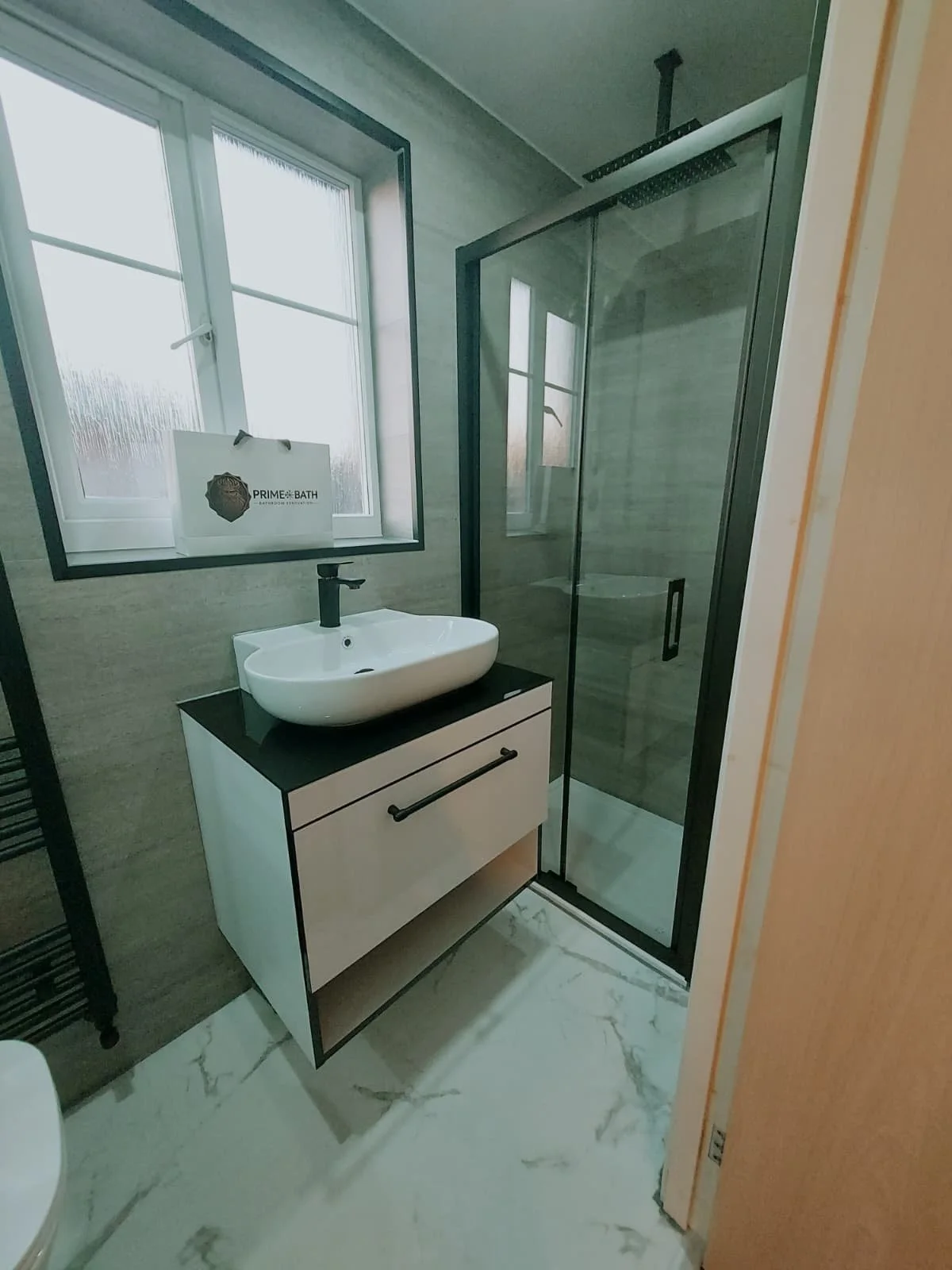 Completed renovation of the same bathroom with new shower, basin and wall panels